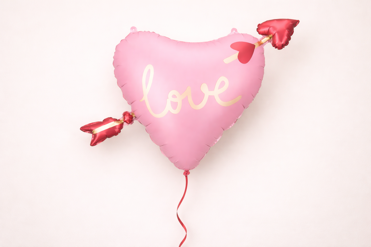 Heart-shaped balloon with 'love' text on a light pink background