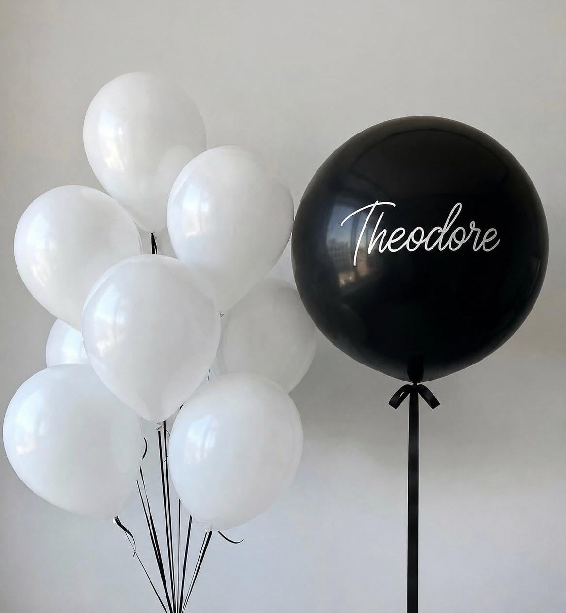 Personalised black jumbo balloon with white helium balloons and elegant black ribbon