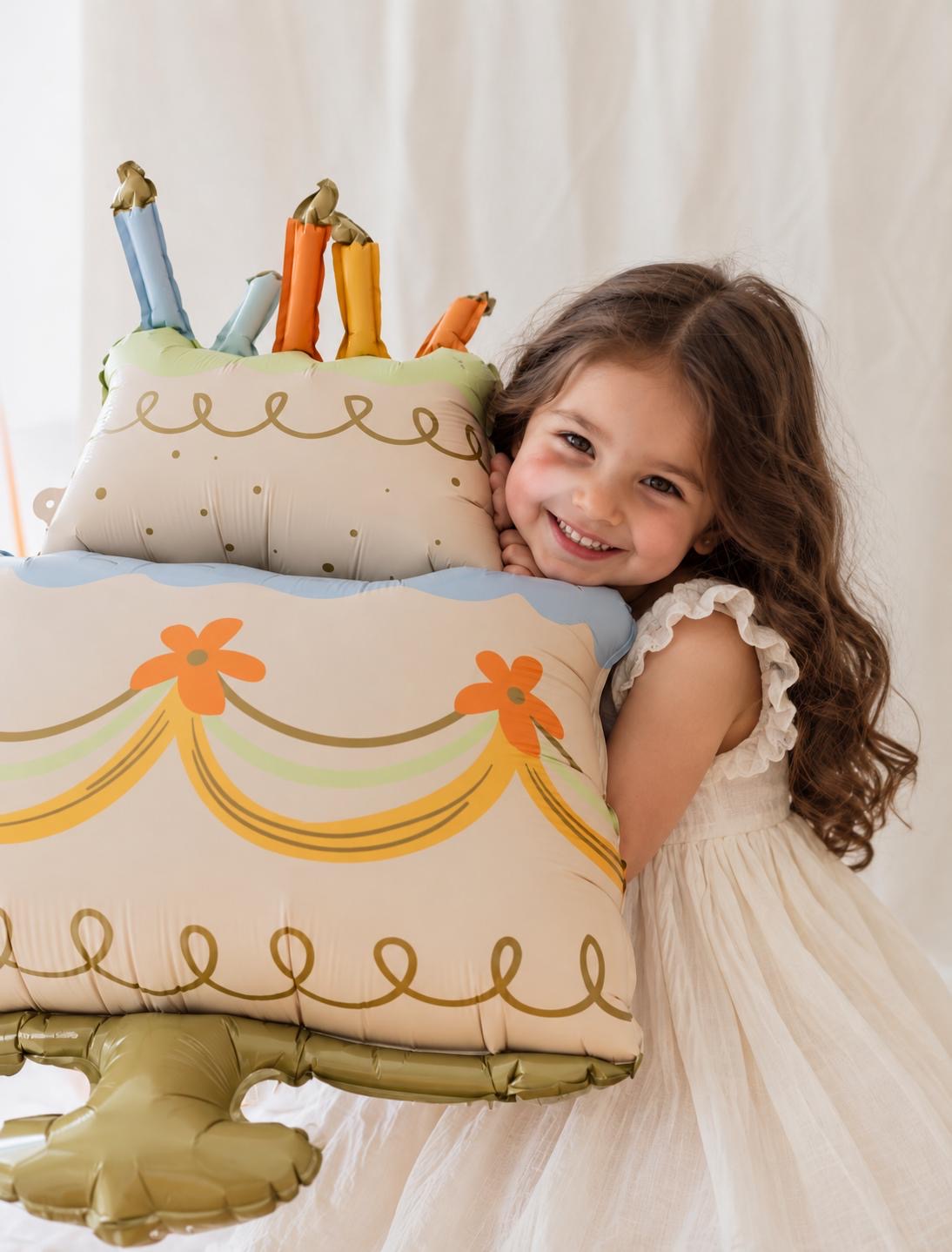 The Cake Edit helium-filled birthday cake foil balloon featuring pastel colours, decorative candles, floral details and gold accents.