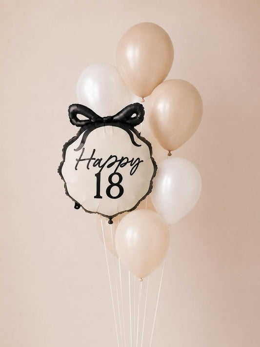 Elegant 18th birthday balloon bouquet featuring a Happy 18 bow foil balloon paired with nude, ivory and white helium balloons.