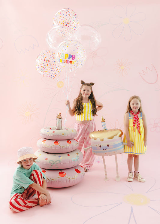 The Confetti Birthday Edit balloon arrangement featuring colourful confetti-print orb balloons, a Happy Birthday orb balloon, a pastel birthday cake balloon and a smiling cupcake balloon.