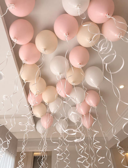 The Floating Edit ceiling helium balloons in soft pink, white and neutral tones with hanging ribbons