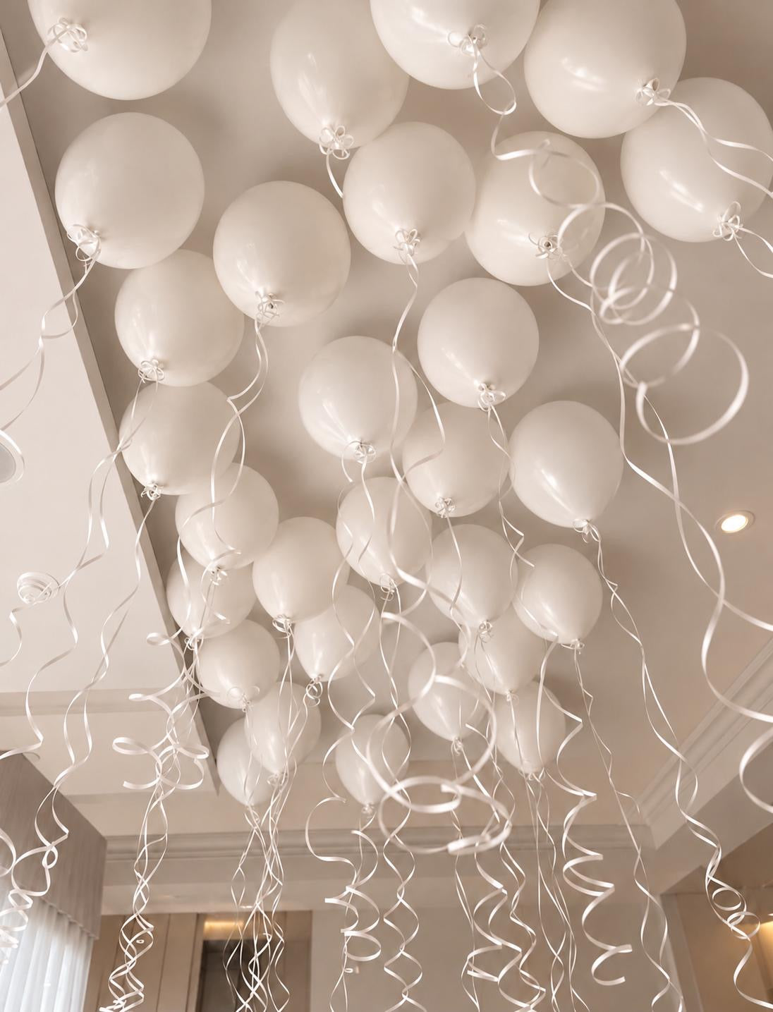 The Floating Edit ceiling helium balloons in white tones with hanging ribbons