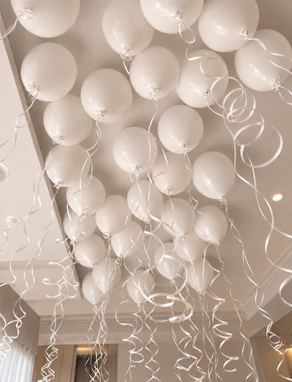 The Floating Edit ceiling helium balloons in white tones with hanging ribbons