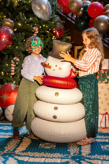 The Frosty Edit giant standing Christmas snowman foil balloon featuring a cheerful snowman with a festive top hat, red scarf and white rounded body, displayed beside a Christmas tree.