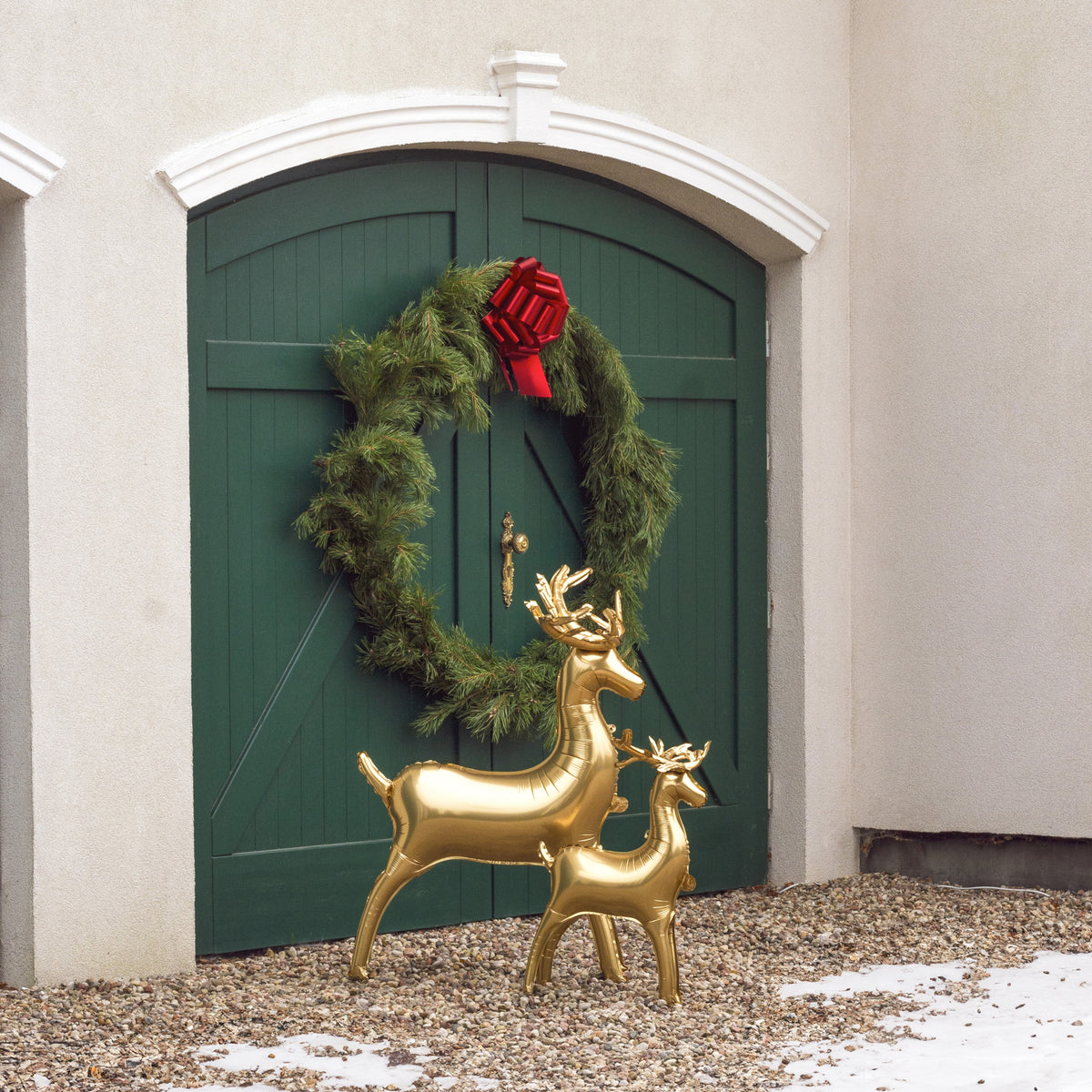 The Golden Reindeer Edit featuring two elegant metallic gold standing reindeer foil balloons displayed in front of a festive green doorway with a Christmas wreath.
