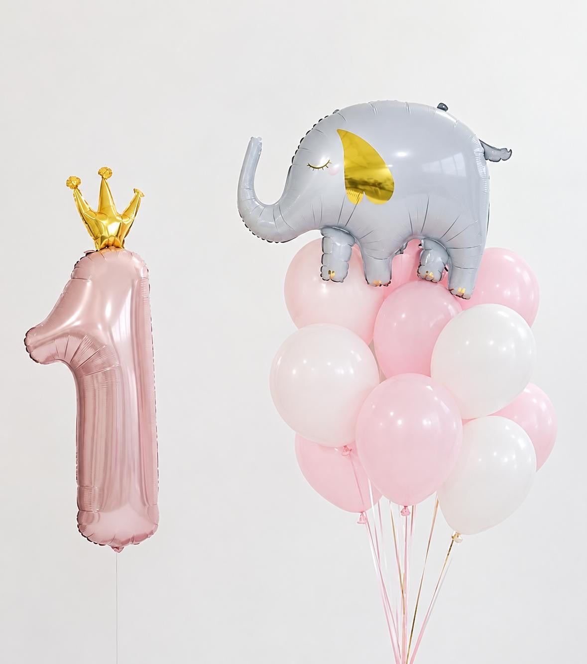 The Little Royal Edit birthday balloon arrangement featuring a pink number 1 with gold crown, elephant foil balloon and soft pink and white helium balloons.
