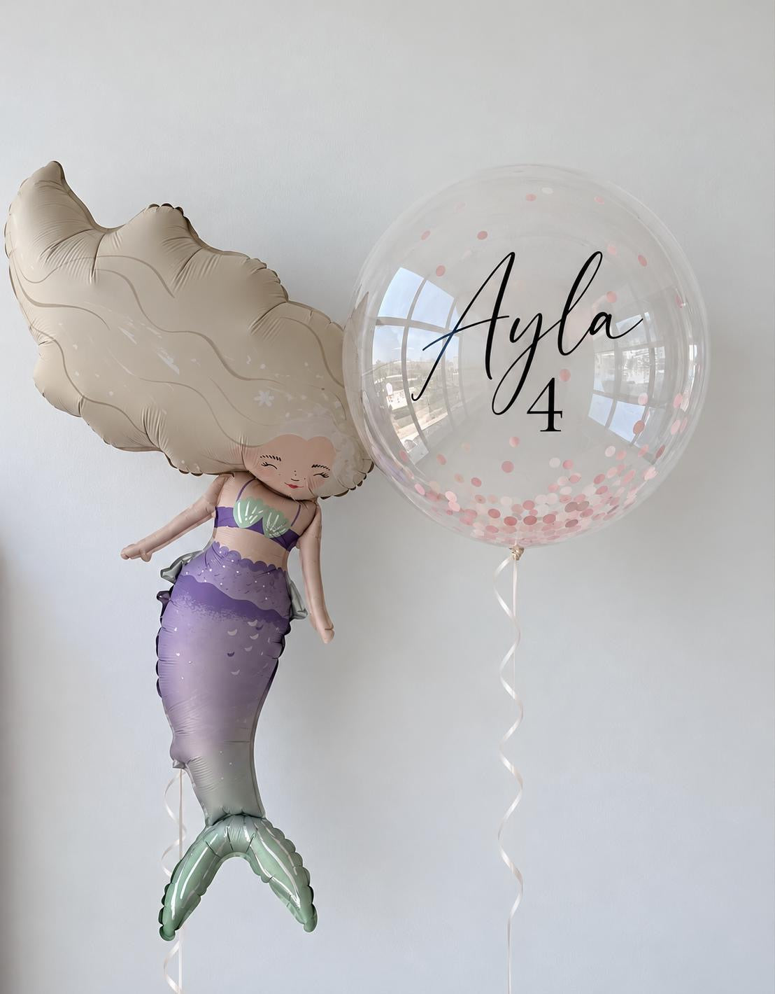 The Mermaid Wishes Edit personalised birthday balloon arrangement featuring a pastel mermaid foil balloon and clear confetti bubble balloon with a custom name and age.