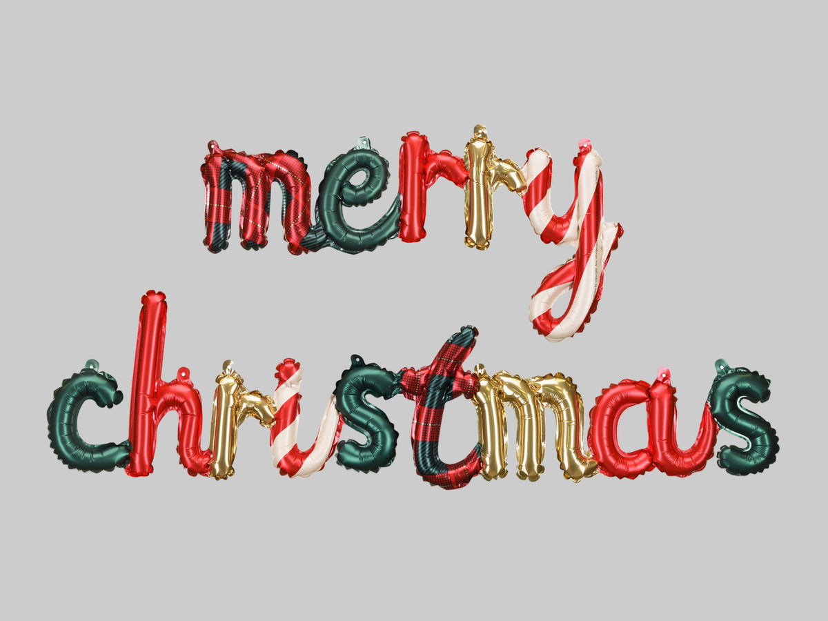 The Merry Christmas Edit festive foil balloon letter banner spelling Merry Christmas in metallic red, forest green, gold, candy cane stripes and red tartan patterns.