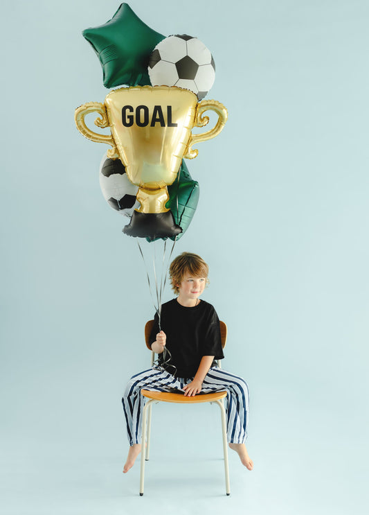 The Winning Goal Edit helium balloon bouquet featuring a gold GOAL trophy foil balloon, two black and white soccer ball balloons and two forest green star balloons.